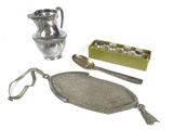 a silver pitcher, spoon, and other items on a white surface