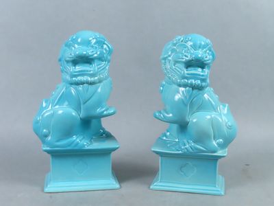 paire de statuettes « foo foo » émaillées de bleu, posées sur des socles, sur fond gris