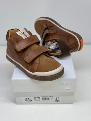 des chaussures de bébé en cuir marron avec des bandes Velcro, posées sur une boîte blanche