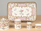 four pieces of porcelain on a table with a tray and cups