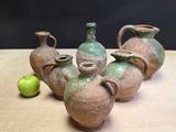 four vases sitting on a table with an apple in the background