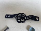 a black leather belt with a flower on it