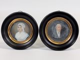 deux portraits encadrés représentant un homme et une femme, dans des cadres noirs et dorés