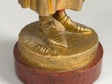 bronze statue of a man in a robe and shoes on top of a wooden base