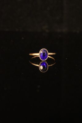 a close up of a gold ring with a blue stone