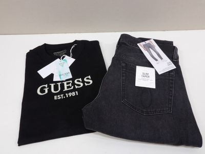 un jean Guess posé sur une table, à côté d'un t-shirt