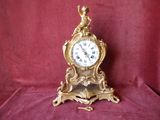 a gold clock with a bird on top of it
