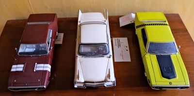 Plusieurs petites voitures sont alignées sur une table en bois