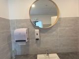 a bathroom with a sink, mirror, and toilet paper dispenser