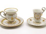 two cups and saucers sitting on a white table