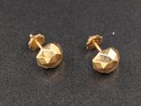 une paire de boucles d'oreilles en or sur une surface noire