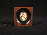 a miniature picture of a woman in a green dress in a wooden frame