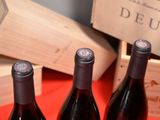 three bottles of red wine sitting on a table next to a wooden box