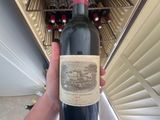 a person holding a bottle of wine in front of a wine cooler