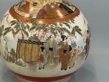 a vase with a painting on it sitting on a table