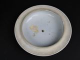 a white plate with a bird on it on a black surface