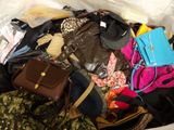 a bag full of clothes and handbags sitting on a bed
