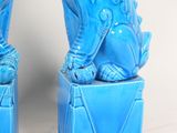 pair of blue foo foo dogs sitting on blue boxes on a white background