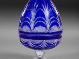 un œuf en verre bleu posé sur un socle