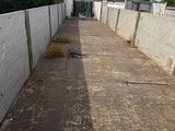 an empty alley with a fence and a building in the background