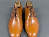 pair of brown leather shoes with laces on them on a gray surface