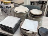 many plates and bowls on a table in front of a window