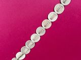 a close up of a silver bracelet on a pink surface
