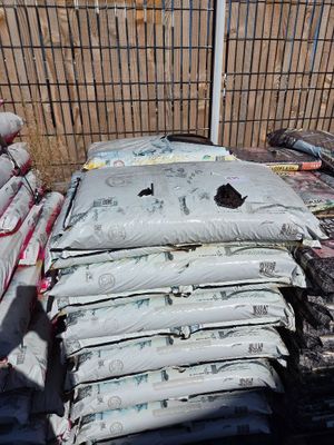 many bags of cement sitting on the ground next to a fence