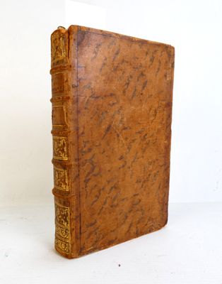 un vieux livre à la couverture marron posé sur une table blanche