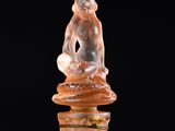 a glass bottle with a figurine sitting on top of it