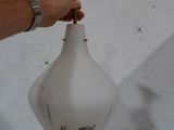 une personne tenant un vase blanc orné d'une clochette dorée