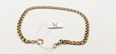 gros plan d'un bracelet en chaîne en or sur une surface blanche