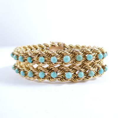 a close up of a gold and turquoise bracelet on a white background