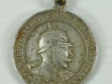 an old silver medal with a picture of a man wearing a hat