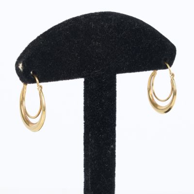 a close up of a pair of gold hoop earrings on a black stand