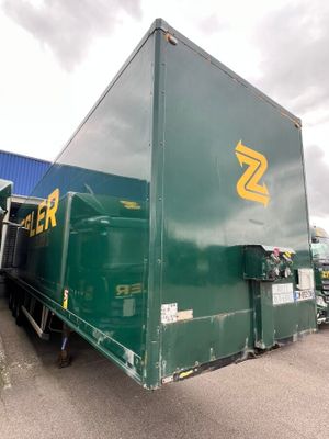 a green semi truck parked in front of a blue building