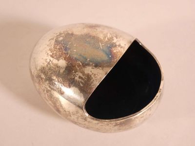 un objet argenté avec un centre noir sur une surface blanche