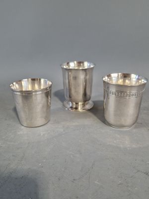 trois tasses en argent posées sur une table, l'une à côté de l'autre
