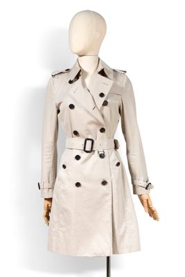 un mannequin blanc vêtu d'un trench-coat, posé sur un socle