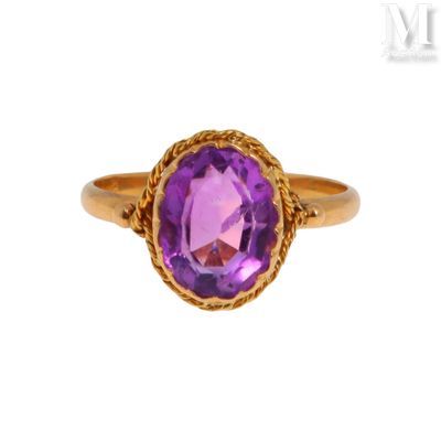gros plan d'une bague en or avec une pierre violette