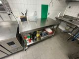 une grande table en inox dans une cuisine, sur laquelle sont disposés de nombreux objets