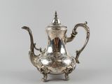 an antique silver tea pot with a handle on a stand
