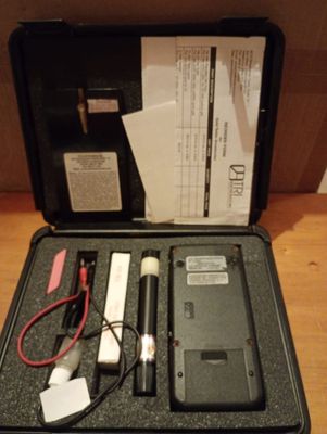 une mallette noire contenant du matériel électronique, posée sur une table en bois