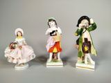 trois figurines en porcelaine représentant des enfants vêtus de costumes d'époque