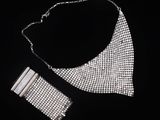 une image représentant un collier et un bracelet en argent sur fond noir