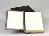 an open book sitting on top of a white table next to a black book