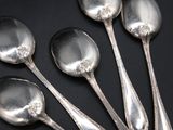 five silver spoons are lined up in a row on a black surface