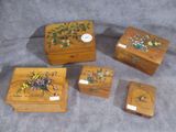 quatre boîtes en bois ornées de motifs floraux, posées sur une surface grise