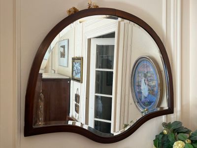 a mirror on the wall above a vase of flowers