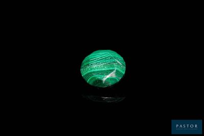 un gros plan sur une boule de marbre vert posée sur une surface noire